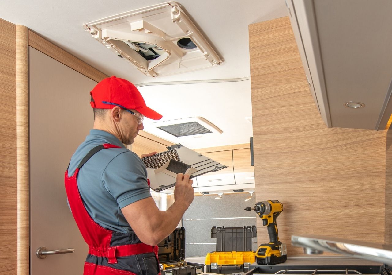 Close-up of a technician diagnosing a rooftop RV AC system with tools in hand