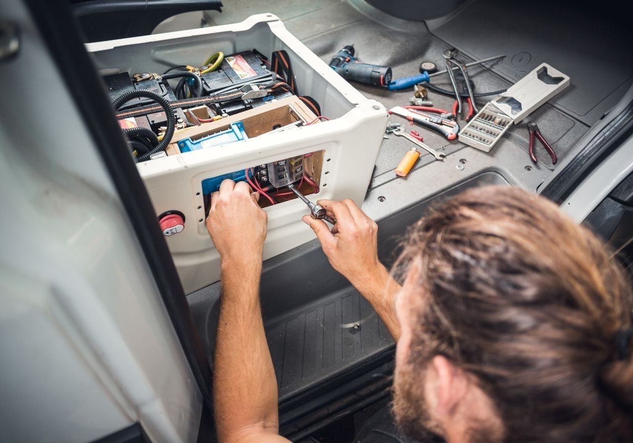 Technician diagnosing RV fuse box and electrical wiring for power issues